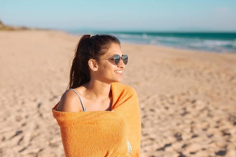 Young woman with towel sandy beach