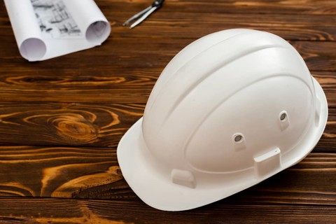 Flat lay construction helmet with plans background