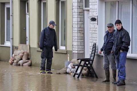 Flooded street and sandbags piled up in front of doors at Nederzwalm
