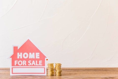 Home sale icon with stacked coins wooden desk