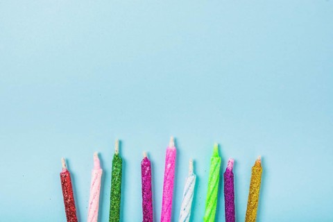 Row colorful sparkling candles blue backdrop