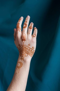 Woman hand with mehndi near blue textile