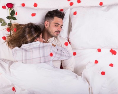 Young couple sleeping bed with rose petals