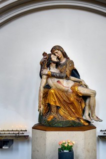 Pieta with sacrificial candles and floral decoration