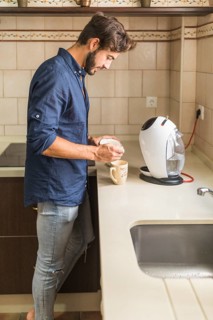 Young man standing kitchen preparing coffee