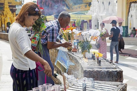 Burmese girl lighting incense sticks at the Shwedagon Pagoda
