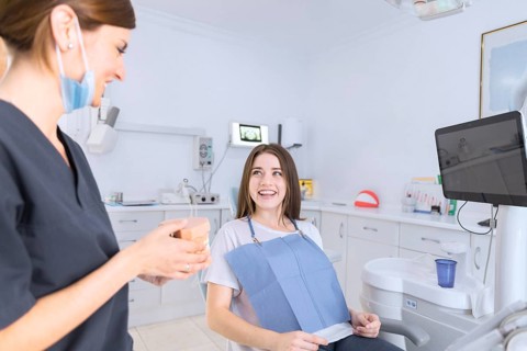 Female dentist showing teeth model smiling patient