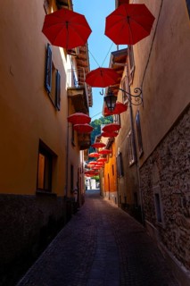 City Street in Porto Ceresio with Hanging Umbrellas in a Sunny Summer Day in Porto Ceresio