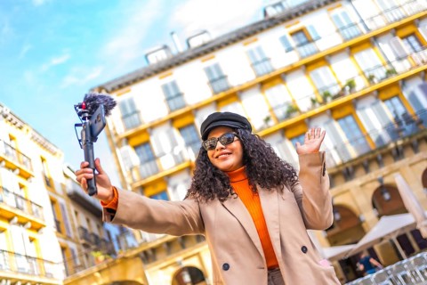 Latin influencer performing a life video using a mobile phone visiting a city in winter