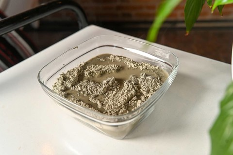 Masseuse preparing mixing clay and water for anti inflammatory massage in spa center