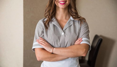 Close up smiling chambermaid standing with her arms crossed