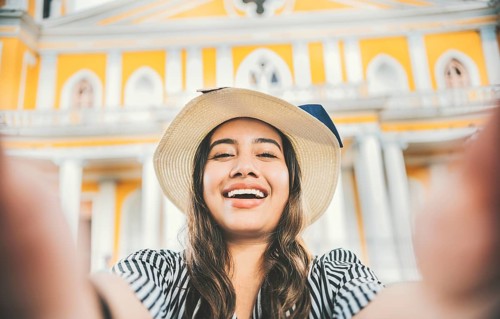Smiling tourist girl in hat taking a selfie in a square. Lifestyle of tourist girl in hat taking a selfie in a square. Granada