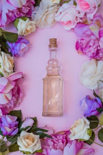 High angle view essential oil surrounded with fresh flowers pink background