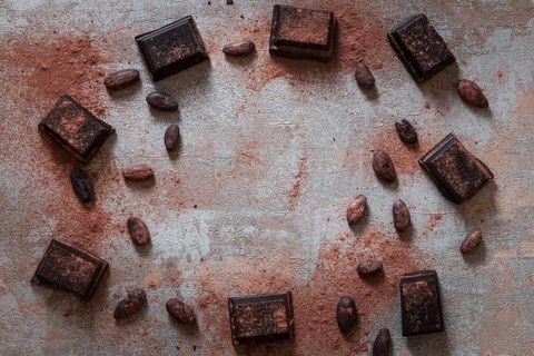 Overhead view broken chocolate bas with cocoa powder raw beans