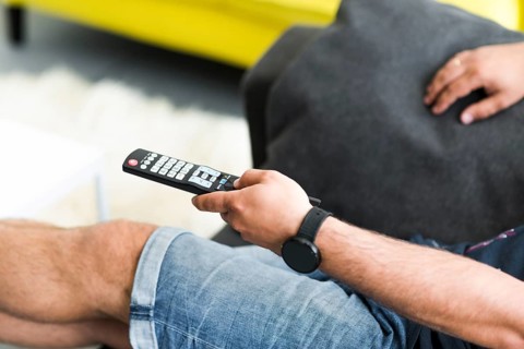 Close up man s hand holding television remote control