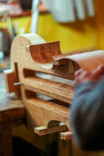Luthier artisan violin maker carve sculpt chisel ribs of a new classical model cello in workshop Cremona Italy