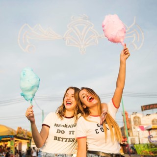 Two happy female friends holding candy floss