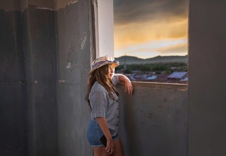 Young woman tourist looking at the sunset through an old window in Granada