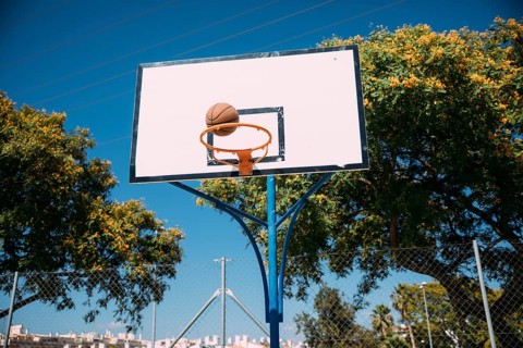 Basketball falling into hoop blue sky