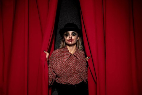 Make up woman holding red theatre curtain