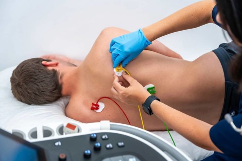Nurse placing electrodes on the back of a cardiology patient during the cardiac test of the electrocardiogram