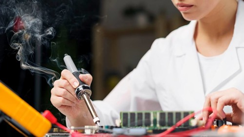 Female technician with soldering iron electronics board