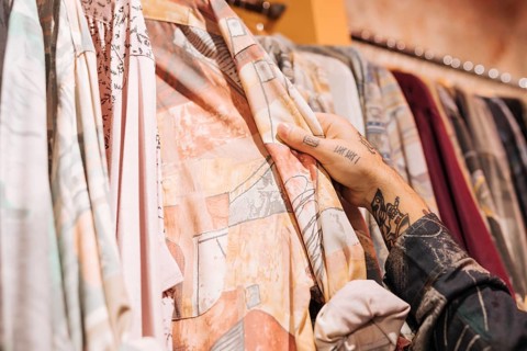 Close up male customer s hand choosing shirt hanging rail shop