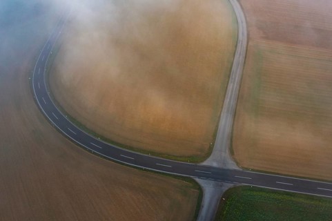 Drone view of a rural landscape shrouded in dense morning fog with a road junction near Prambachkirchen