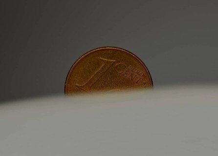 A 1 cent coin as a macro shot in the slot of a piggy bank