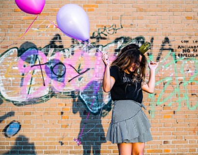 Girl holding balloons front graffiti wall