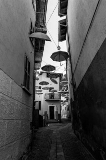 City Street in Porto Ceresio with Hanging Umbrellas in a Sunny Summer Day in Porto Ceresio