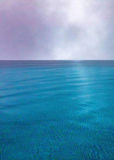 Rippled water surface during rain in swimming pool with dramatic cloudy sky