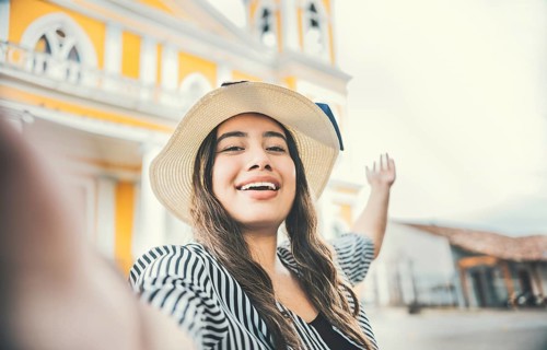 Lifestyle of tourist girl in hat taking a selfie in a square. Granada