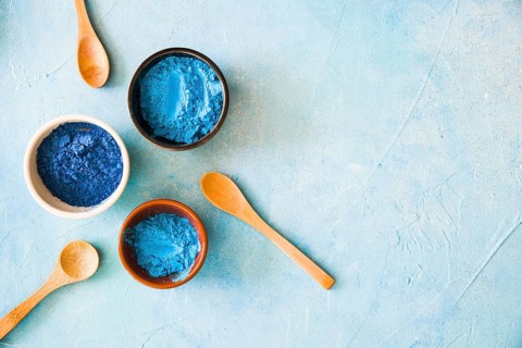 Bowls with holi color powder wooden spoon painted background