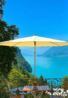 Grandhotel Giessbach with Terrace and Parasol with Furniture and View over Lake Brienz with Mountain in a Sunny Summer Day in Brienz
