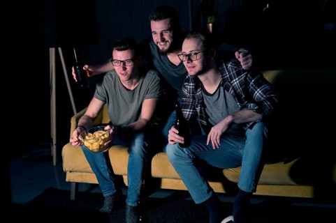 Male friends watching sports tv together with snacks