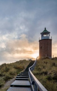 Wooden footbridge and stairs through the dunes to the lighthouse