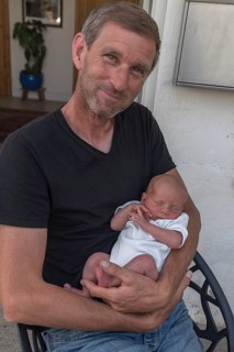 Young grandpa with his newborn grandson in his arms