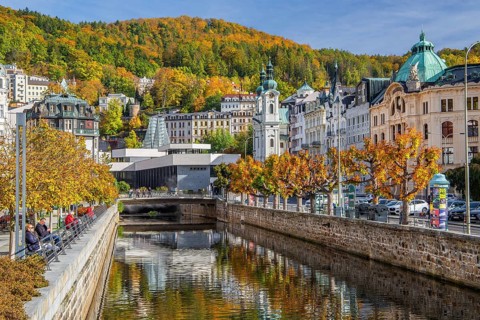 Tepla River in the town centre with the spa colonnade and the Church of St. Mary Magdalene in autumn