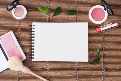 Blank spiral notepad surrounded with cosmetics products placemat