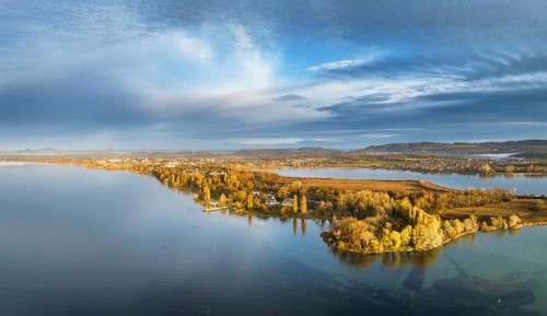 Aerial panorama of the Mettnau peninsula in western Lake Constance illuminated by the morning sun with the spa centre