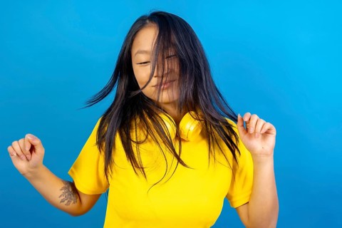 Studio photo with blue background of a chinese woman with headphones dancing freestyle