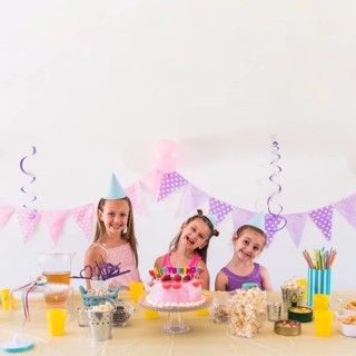 Happy friends enjoying birthday party with tasty snack cake table