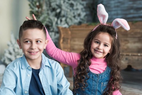 Girl bunny ears making horns with fingers boy