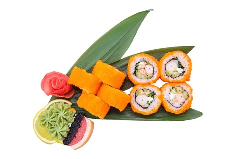Overhead view of shrimp roll with avocado and caviar on top served on bamboo leaves