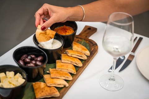 Cropped close-up photo of the hand of a woman dipping pitta bread into sauce in a luxury restaurant