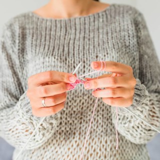 Close up female s hand crocheting with pink thread
