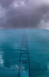 Rippled water surface during rain in swimming pool with dramatic cloudy sky