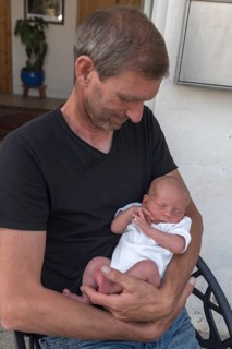 Young grandpa with his newborn grandson in his arms