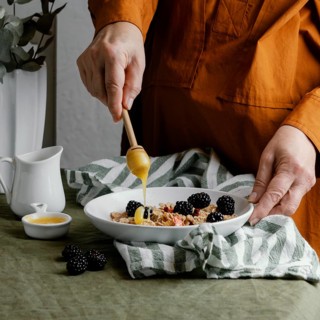 Close up hand pouring honey cereals